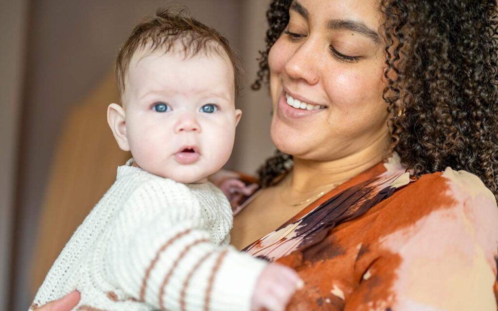 happy-nanny-holding-baby-in-tan-clothes